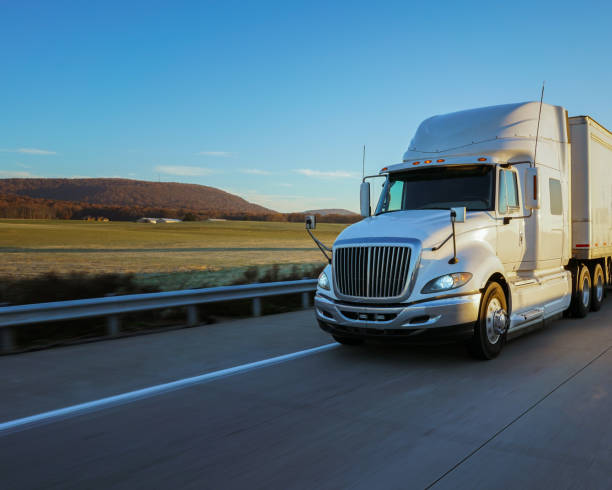 semi tractor trailer driving on the highway in the evening